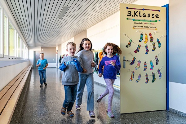 Kinder rennen durch den Gang im Schulhaus