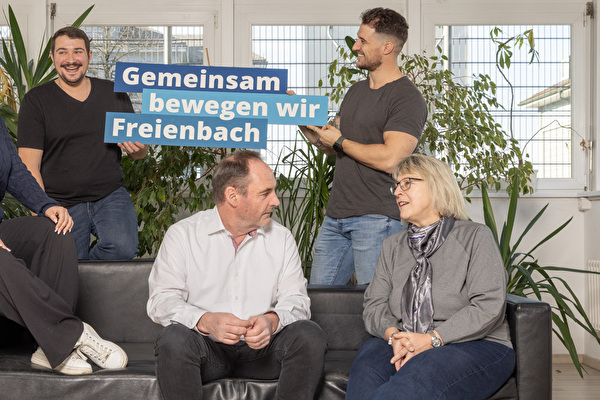 Verschiedene Mitarbeiter sitzen auf dem Sofa und Unterhalten sich in der Mitte der Claim Gemeinsam bewegen wir Freienbach