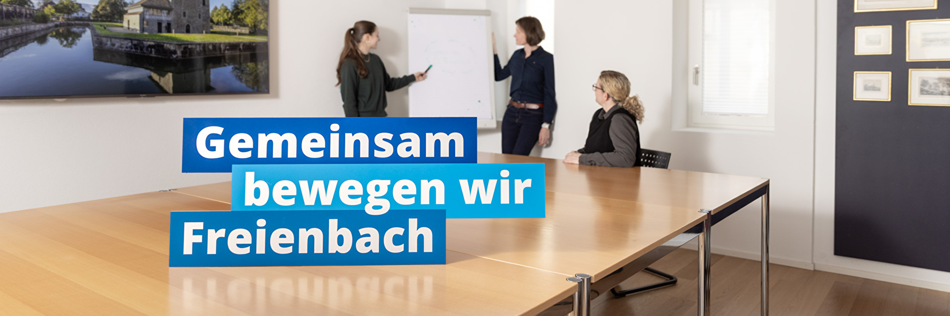 Sitzungszimmer mit Mitarbeitenden und dem Claim Gemeinsam bewegen wir Freienbach
