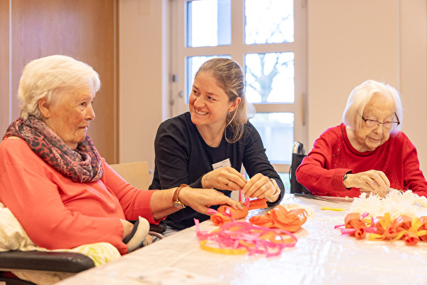 Pflegerin bastelt mit älteren Frauen