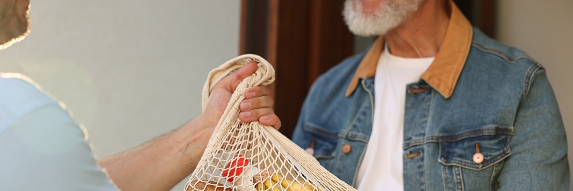 Mann übergibt älterem Mann Essenstasche