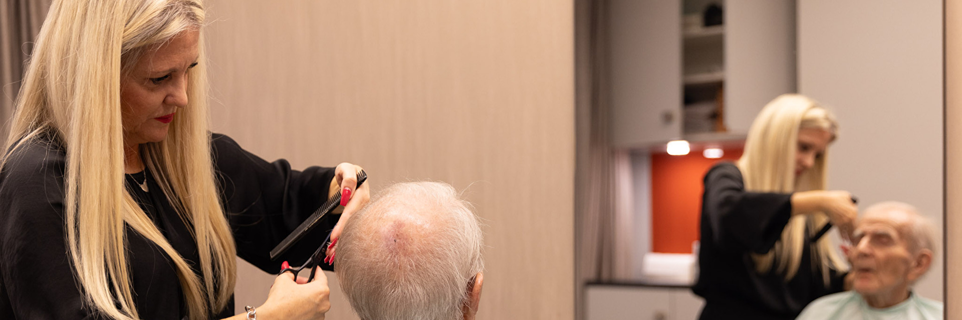 Frau schneidet älterem Mann die Haare