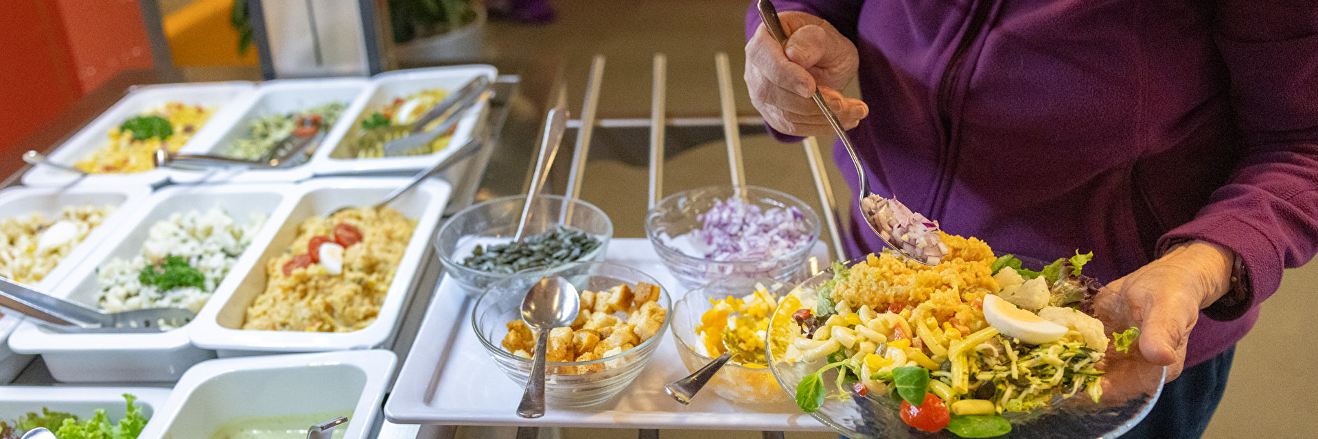 Frau schöpft vom Salatbuffet