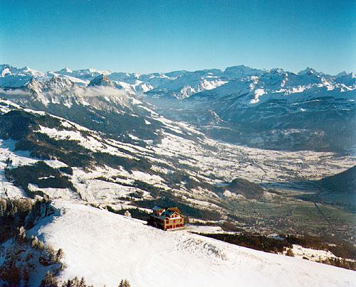 Der Wildspitz ist der höchste Punkt (1580 Meter über Meer) im Kanton Zug und ist Teil des Rossbergs. Das Bild hat Nostalgiecharakter: Das Restaurant brannte im Januar 2000 bis auf die Grundmauern nieder. Bis ein neues Restaurant im Jahre 2002 eröffnet wird, steht eine Baracke. Im Hintergrund der Talkessel von Schwyz mit dem grossen und dem kleinen Mythen (links), dahinter die Urner Alpen.
