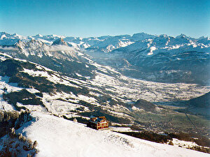 Der Wildspitz ist der höchste Punkt (1580 Meter über Meer) im Kanton Zug und ist Teil des Rossbergs. Das Bild hat Nostalgiecharakter: Das Restaurant brannte im Januar 2000 bis auf die Grundmauern nieder. Bis ein neues Restaurant im Jahre 2002 eröffnet wird, steht eine Baracke. Im Hintergrund der Talkessel von Schwyz mit dem grossen und dem kleinen Mythen (links), dahinter die Urner Alpen.