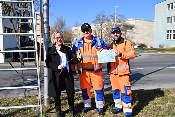 Ernesto Caccese und Giovanni Bezerra vom Unterhaltsteam des Werkhofs Zug mit Stadträtin Barbara Gysel beim Montieren eines LoRa WAN-Sensors zur Temperaturmessung.