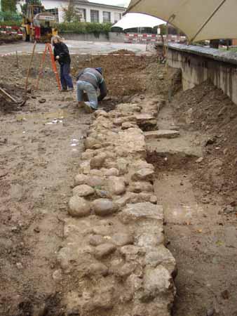 15. Oktober 2004: Das noch vorhandene Mauerstück von etwa 7,50 Meter Länge und rund 80 Zentimeter Dicke, nördlich des alten Kirchenchores gelegen, ist nun vollständig freigelegt. Rechts des Männerfusses weist es einen Knick nach Süden auf. Hier dürfte der Chor eines Vorgängerkirchleins begonnen haben.