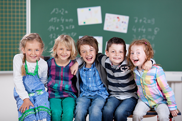 Aufstellte Kinder sitzen vor Wandtafel