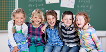 Aufstellte Kinder sitzen vor Wandtafel
