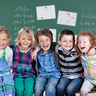 Aufstellte Kinder sitzen vor Wandtafel