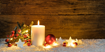 Brennende weisse Kerze mit roten Kugeln