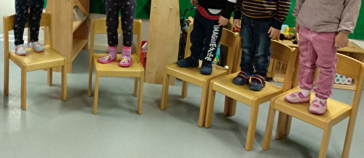 Spielgruppenkinder stehen auf den Stühlen