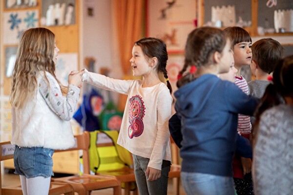 Zwei Mädchen geben sich beim Spielen im Kindergarten die Hand.