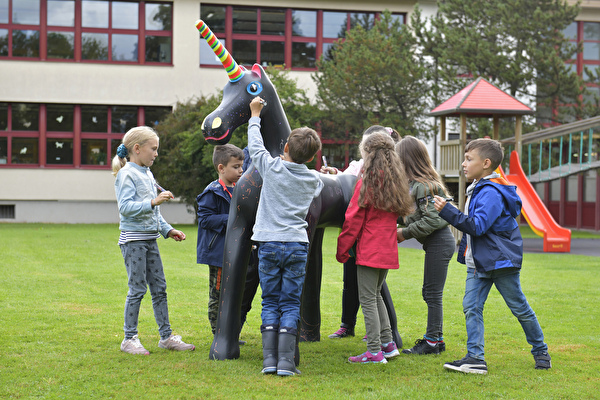 Schülerinnen und Schüler bemalen ein Einhorf.