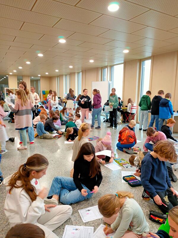 Eine kunterbündte Kinderschar am Bearbeiten der Dossiers