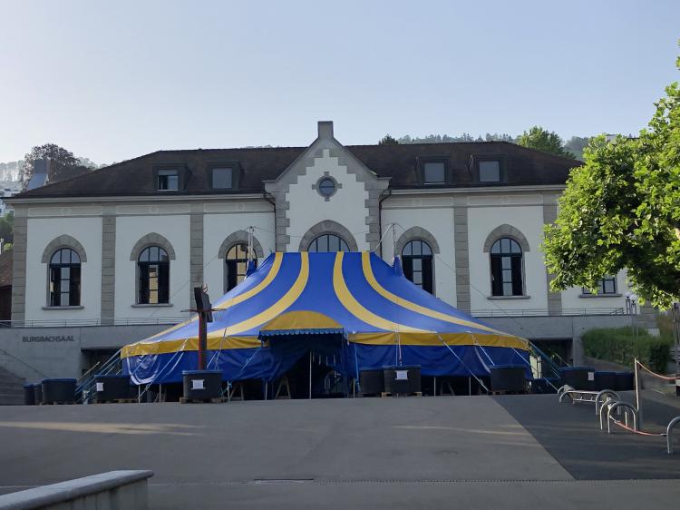 Blau, gelbes Zirkus Zelt steht auf dem Pausenplatz vor dem Burgbachsaal.