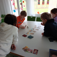 Schüler sitzen am Tisch und spielen Kartenspiele