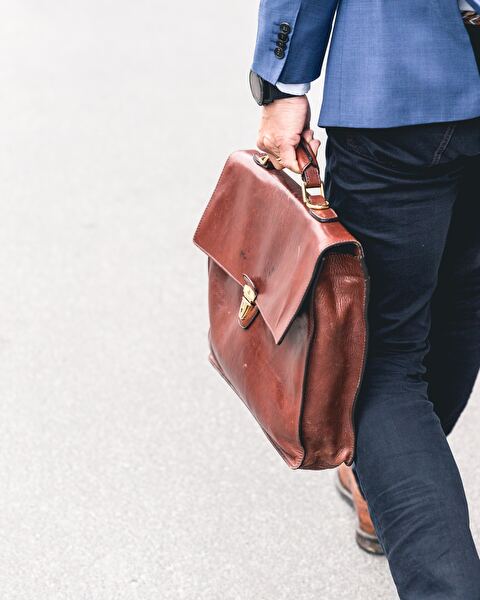 Man im Anzug mit Arbeitstasche aus Leder von hinten, Fokus auf Tasche