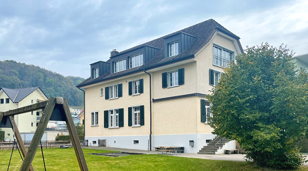 gelbes Haus mit grünen Fensterläden mit Spielplatz