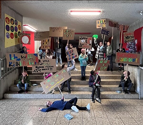 Kinder demonstrieren mit selbstgebastelten Tafeln und Sprüchen gegen Beleidigungen an der Schule