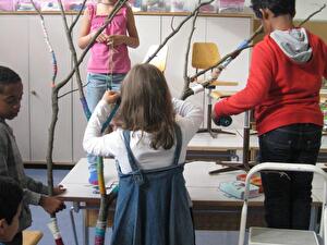 Fleissig umwickeln die Schülerinnen und Schüler den grossen Ast.