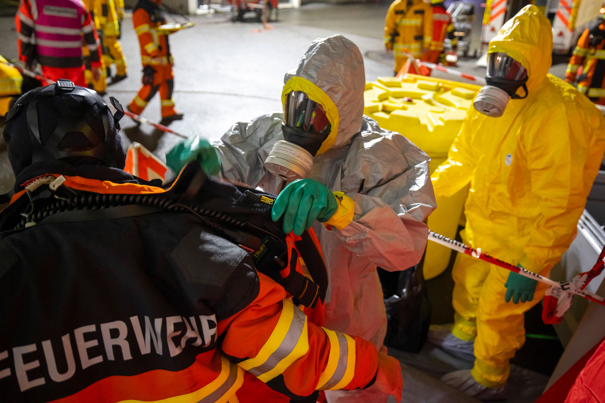 Ein Feuerwehrmann in Schutzausrüstung nimmt einem Kollegen, der an der Rettungsaktion beteiligt war, die verschmutzte Ausrüstung ab.