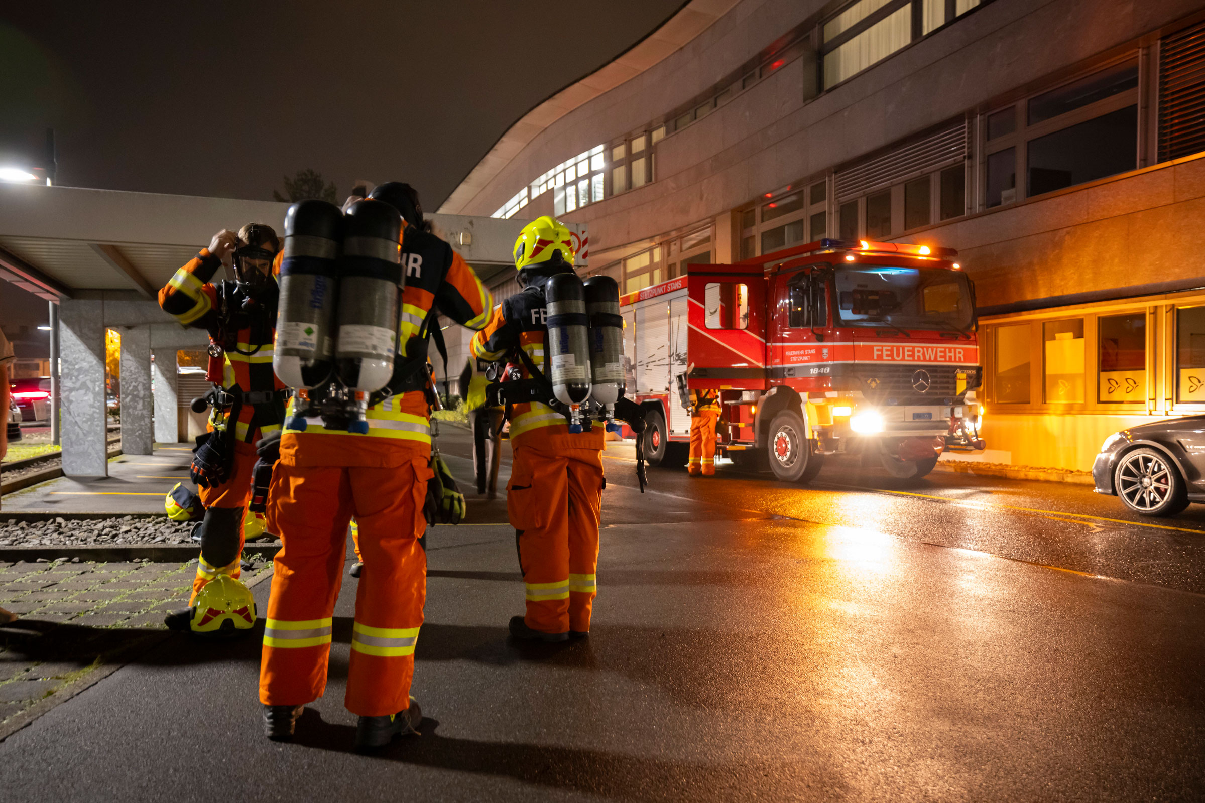 Feuerwehrleute rüsten sich auf dem Parkplatz des Spitals mit Atemschutzgeräten aus.