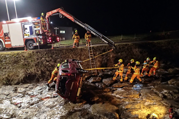 Ein Personenwagen liegt im Bekenrieder Lielibach. Eine Person hat sich beim Unfall verletzt, konnte sich aber selber befreien. Die Strassenrettungsgruppe sichert das Fahrzeug und holt es auf die Strasse zurück.