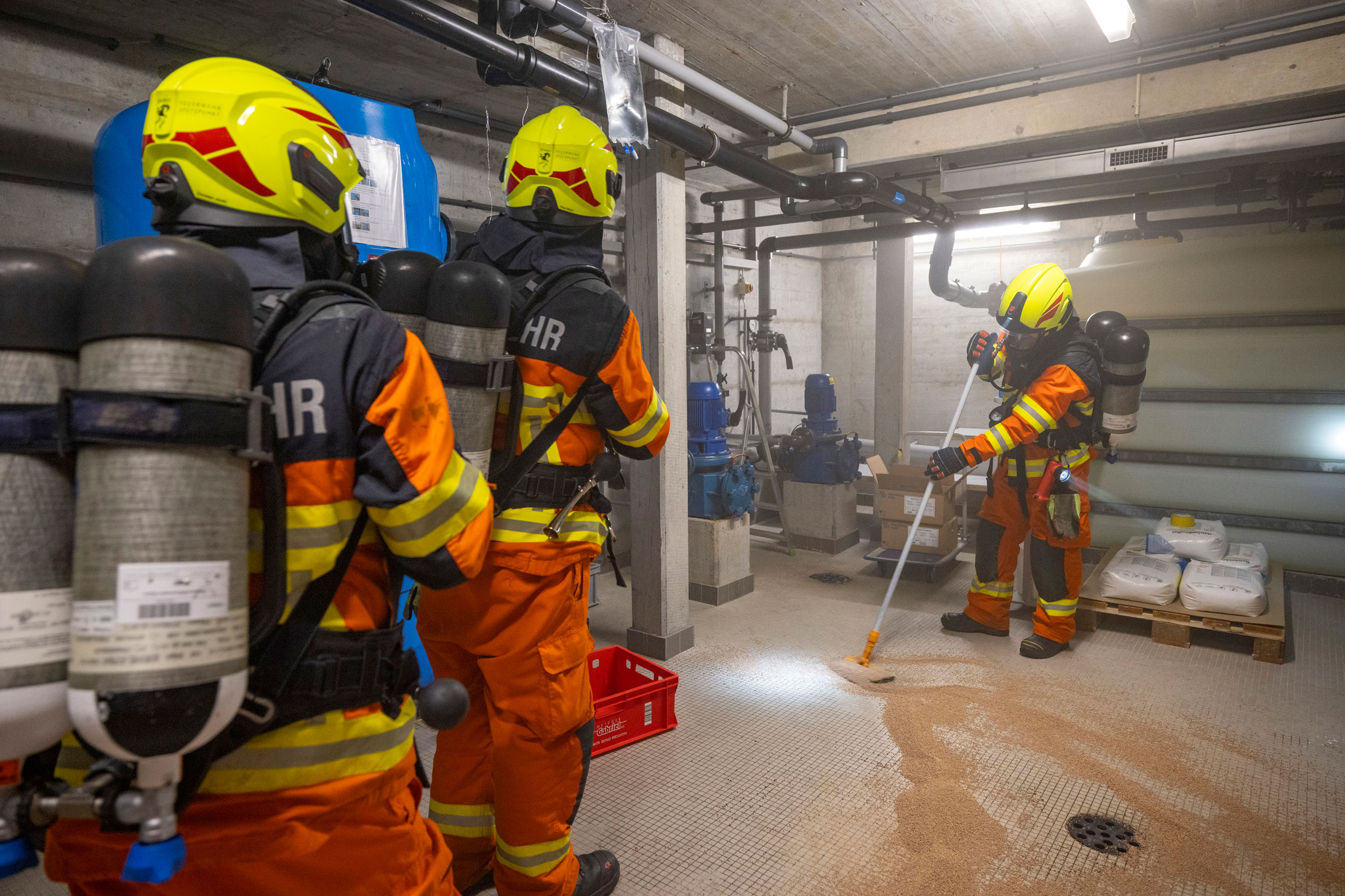 Feuerwehrleute rücken zum Unfallort vor, beurteilen die Situation und fangen die weiterhin auslaufende Chemikalie auf.