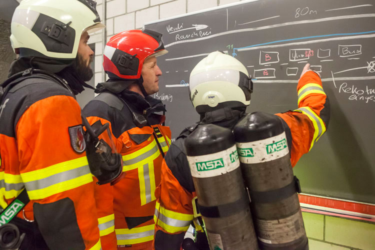 Kursteilnehmer der Stützpunktfeuerwehr Altdorf berichten dem Einsatzleiter, was sie im Tunnel angetroffen haben.