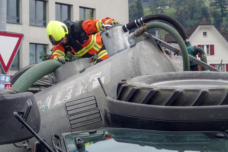 Beim Einbiegen in die Robert-Durrerstrasse kippt ein Traktor mit angehängtem Druckfass auf die Seite. Die Feuerwehr pumpt die Gülle in einen anderen Anhänger und stellt den Traktor wieder auf die Räder.