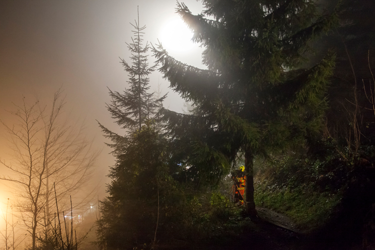 Nach Übungsende räumt ein Feuerwehrmann einen Scheinwerfer am Wanderweg wieder ab.