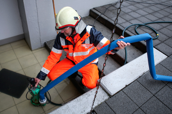 Ein Feuerwehrmann pumpt einen Hauseingang aus.