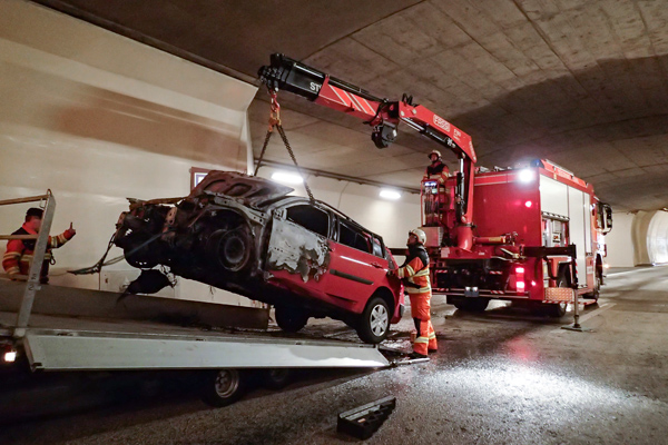 Feuerwehrleute verladen das gelöschte und abgekühlte Auto zum Abtransport.