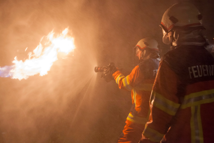 Wie bereits zuvor der Einsatzzug 2 übt der Einsatzzug 1 den Löschdienst. Dabei kommen realistische Simulationsmittel zum Einsatz. An der Gasflamme erproben die Feuerwehrleute die Kühlwirkung des Wasser-Sprühstrahls.