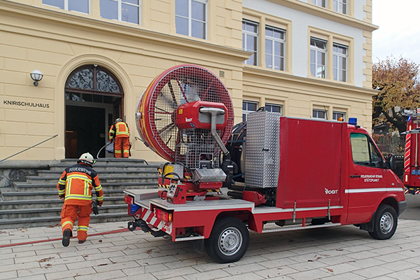 Im Knirischulhaus bricht in einem WC Feuer aus. Die Feuerwehr löscht den Brand und belüftet das Gebäude, während die Schulkinder in der nahen Klosterkirche in Sicherheit warten.