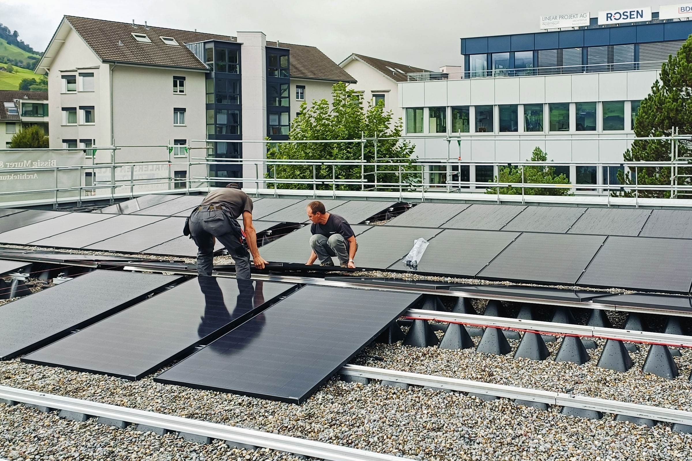 Elektromonteure installieren auf dem sanierten Dach des Feuerwehrgebäudes die neue Solaranlage.