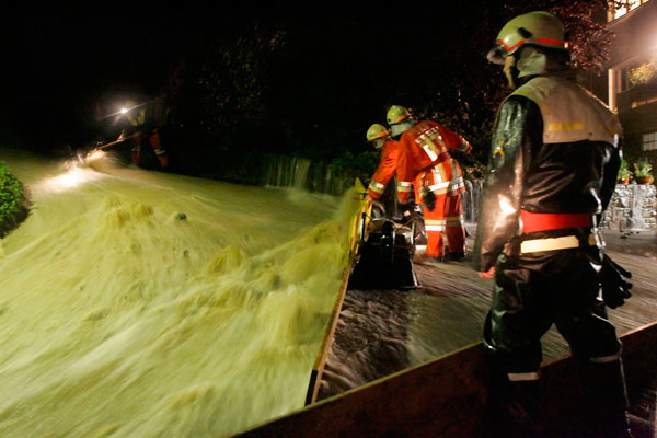 Mit Brettern und Sandsäcken schützt die Feuerwehr die Häuser.