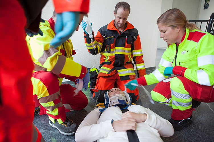 Szene Nr. 4: Um die Zusammenarbeit mit Partnerorganisationen zu zeigen, machen Rettungssanitäter eine Patientin transportbereit.