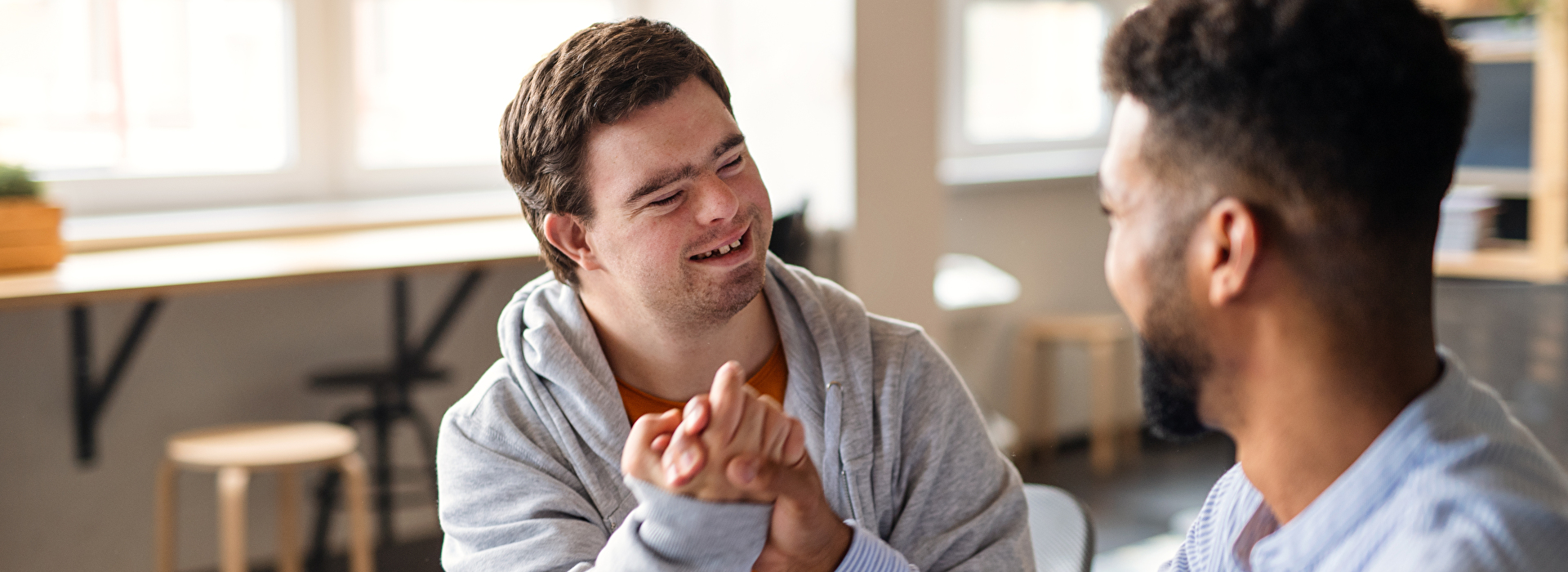 Ein Mann mit Trisomie 21 gibt einem anderen Mann einen Handschlag.