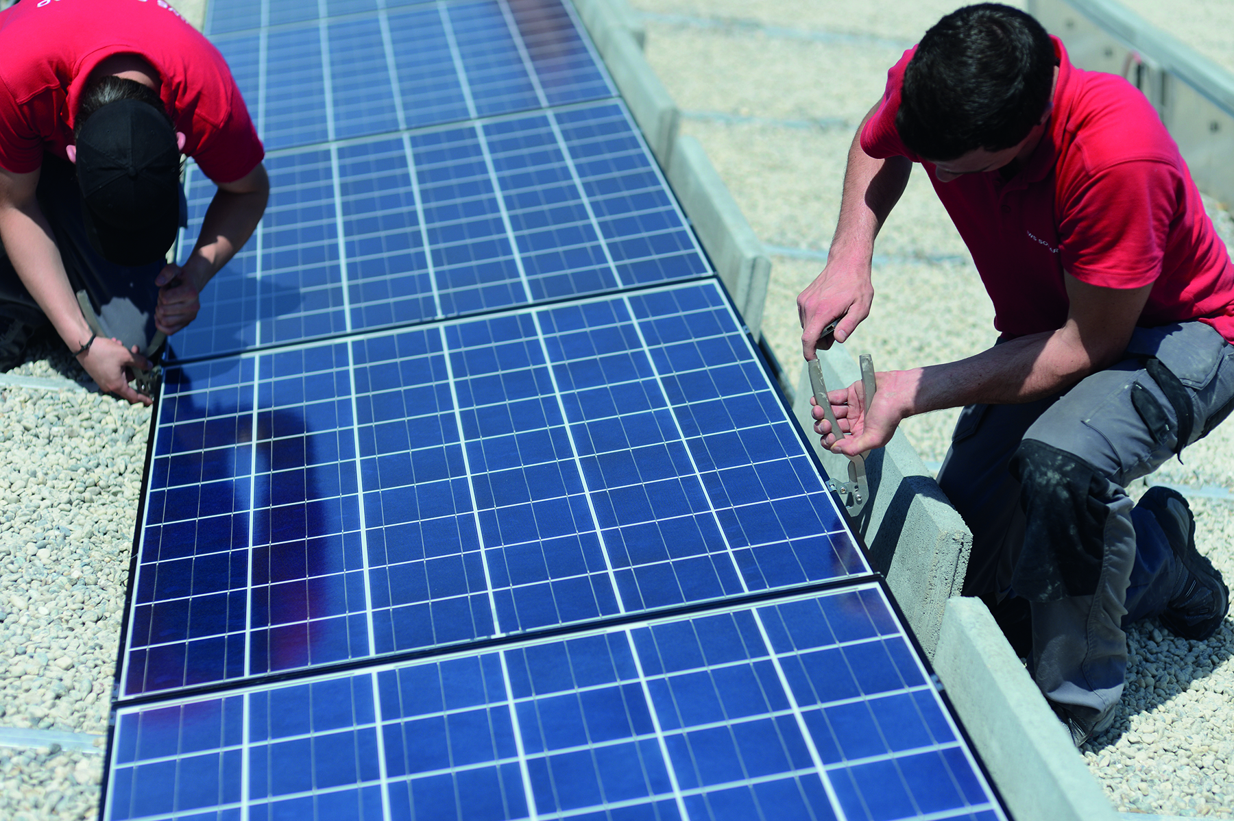 Deux installateurs solaires installent des panneaux solaires sur un toit plat
