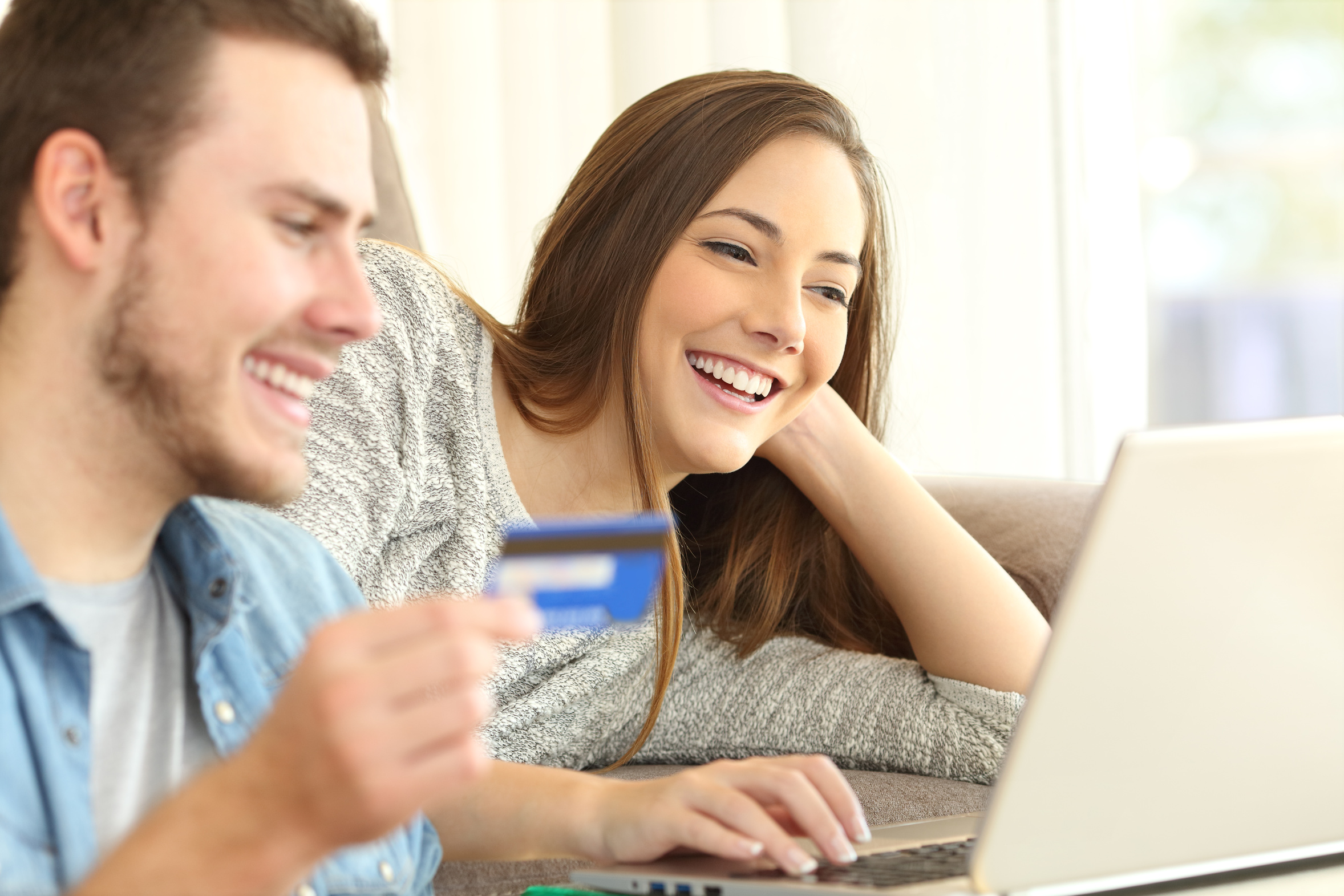 Une femme et un homme avec une carte de crédit devant leur ordinateur portable