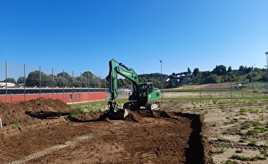 Ein Bagger macht den Aushub auf dem Fussballfeld. Die Obere Erdschicht wird entfernt.