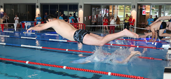 Bild von einem Schwimmer des Wettkampfes von Menschen mit einer Behinderung der vom Block ins Wasser springt.