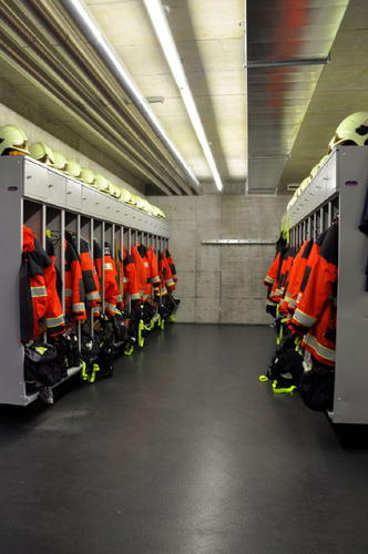 In der Garderobe ist die persönliche Schutzausrüstung (PSA, resp. Brandschutzbekleidung) der Feuerwehrangehörigen deponiert. Hier ziehen sich die Einsatzkräfte innert weniger Sekunden um, damit sie anschliessend in den Einsatz ausrücken können.
Nach einem Einsatz besteht auch die Möglichkeit sich in den separaten Duschen (nicht im Bild) zu reinigen.
