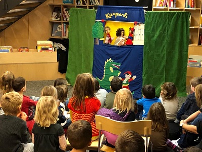 Kinder schauen dem Kasperli-Theater zu.
